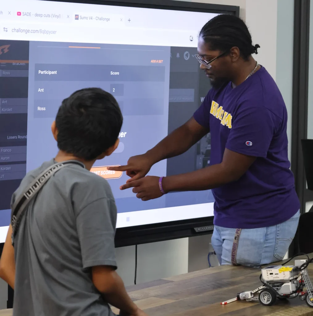 Illuminate STEM instructor teaching a student to code at a smart board